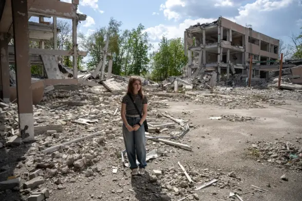 Polina, 14, stands on the ruins of her school, which was bombed by Russian forces in 2022 in Lozova, Kharkiv Oblast, Ukraine, on April 24, 2025. (Dzvinka Pinchuk / The Kyiv Independent)