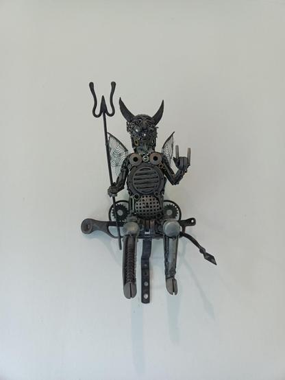 Jätemetallista askarreltu piru istuu seinällä ja näyttää heavytervehdystä