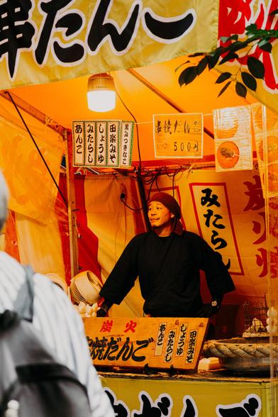 photo of a man standing in his booth selling food, waiting for customers