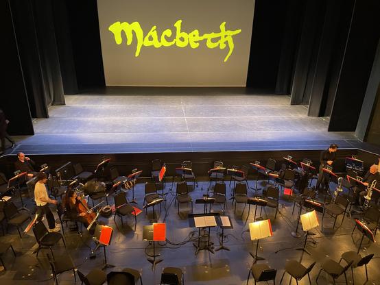 Orchestra pit and bare stage pre-show, with "Macbeth" projected on rear