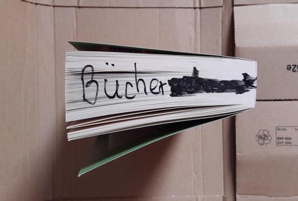 Die Unterseite eines Buches, auf die jemand mit Filzschreiber das Wort "Bücher" (und noch etwas anderes, das dann kräftig durchgestrichen wurde) geschrieben hat.