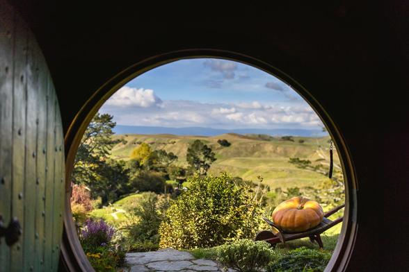 View from Hobit hole - grass and blue sky can be seen through a round door. Standing inside, looking through the open door.