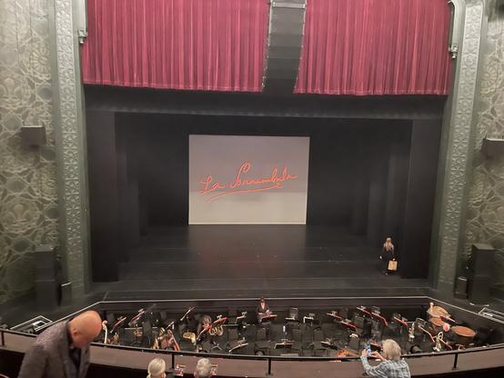 Orchestra pit and stage viewed from mezzanine, with "La Somnabula" projected on rear.