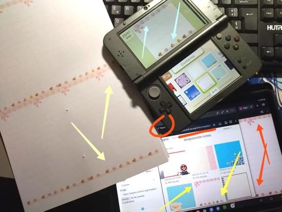 Foto alla mia scrivania, con il modello a decorazioni rosa stampato in A6 su fogli A4, Swapdoodle sul 3DS XL con evidenziato il modello originale, il tablet con aperta la directory in questione sulla finestra di Pignio, e dietro la finestra di Papiellify con aperto il modello.
