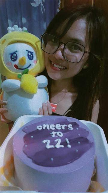 Front: small cake with text "cheers to 22!"
Back: Woman with glasses, smiling while holding a lemon-themeďsnowman plushiefrom Mixue