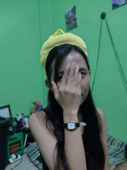 Woman wearing a lemon hat. Covering her face with her right hand. The hat was actually from the snowman plushie