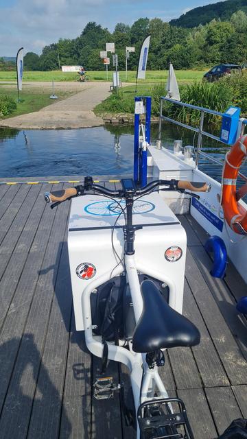 Weißes Lastenrad auf der Fähre im Hintergrund das Ufer der Ruhr.