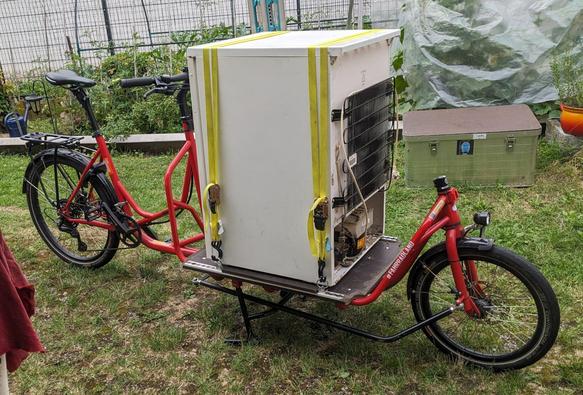 Ein Kühlschrank auf der Ladefläche eines Radkutsche Rapid. Das ist eine Lastenrad in der Long John Bauweise.
