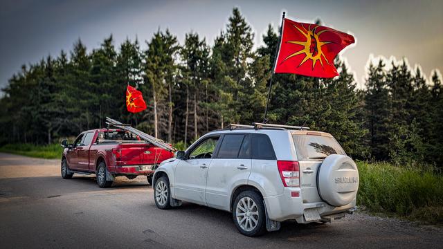 Two vehicles in a forest road in "Quebec" with Mohawk warrior flags