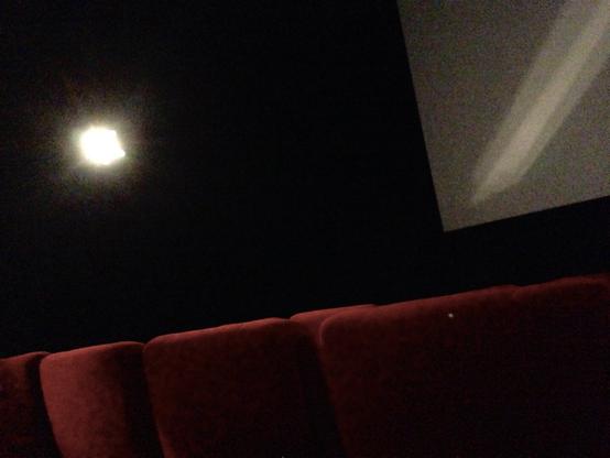 In a movie theater, rows of seats shot from behind, with the screen in the background. (Version françæ) Dans æn salle de cinéma, rangées de fauteuils prix de dos, avec l’écran en arrière-plan.