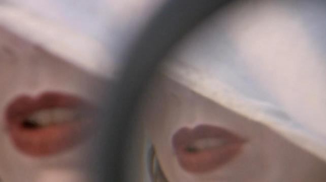 Video still from Infinite Jest showing double lens close up image of actress's heavily glossed lips
