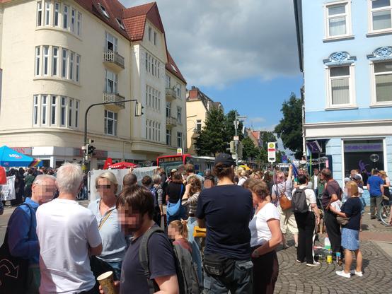 Ecke am Delmemarkt in Bremen Neustadt. Viele Leute mit Schildern und Transpis. Auf der gegenüberliegenden Seite, klein am Rand zu erkennen, der AfD-Stand.