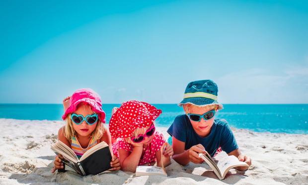 Niños leyendo en una playa. (Getty Images/iStockphoto)