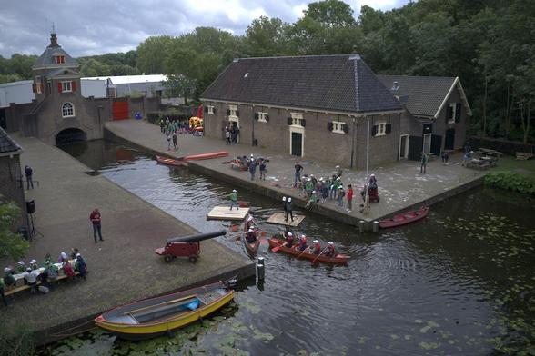Foto van binnenterrein Scoutcentrum Delft, alwaar kinderen in de welpen leeftijd op de kant en in kano's activiteiten hebben