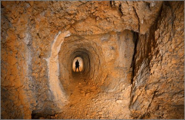Une galerie d'environ deux mètres de haut pour un de large, où l'on aperçoit au loin une silhouette humaine.