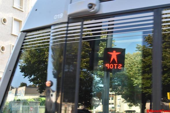 reflet d'un feu de signalisation piéton "Stop" dans les vitres du tramway
