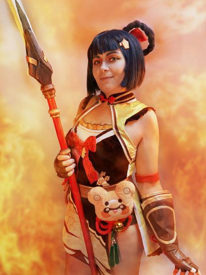 Me cosplaying as Xiangling from Genshin Impact holding a spear surrounded by flames (retouched)