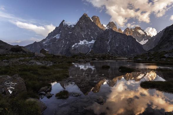 La mole del Monte Pelvoux, en el parque nacional de los Ecrins en los Alpes franceses, reflejado en un remanso del río glaciar en un bonito atardecer