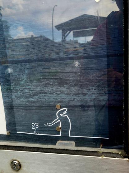 Infotafel mit Ausschnitt, der die Comic Zeichnung 'La Linea' des italienischen Zeichners Cavandoli zeigt. Die als Querulant bekannte Linienstrichfigur, auch 'Lui', wie sein Schöpfer sie nennt, zeigt mit freudestrahlendem Mund auf eine kleine Blume.