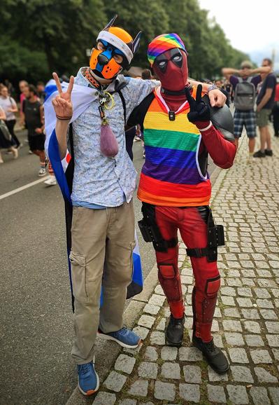 A guy in a Deadpool suit wearing a rainbow top and Bandana arm in arm with Aki