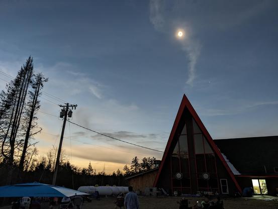 Darkened sky Solar eclipse 2024 above A-frame building in Adirondack Mountains NY