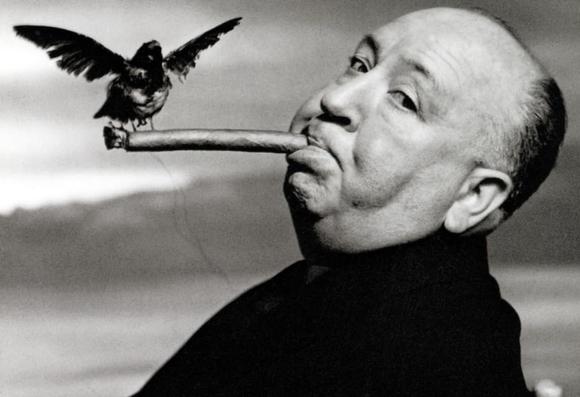 A black and white image of director Alfred Hitchcock in profile while a black bird perches on the long cigar in his mouth. The background is a coastal scene of the Pacific Ocean, given ‘The Birds’ was shot on location in northern California. Hitchcock's eyes are looking at the camera, head titled slightly back.

A black and white image of director Alfred Hitchcock in profile while a black bird perches on the long cigar in his mouth. The background is a coastal scene of the Pacific Ocean, where ‘The Birds’ was shot on location in northern California.

‘The Birds’, is a 1963 American natural horror-thriller film produced and directed by Alfred Hitchcock. Loosely based on the 1952 story of the same title by Daphne du Maurier, it focuses on a series of sudden and unexplained violent bird attacks on the people of Bodega Bay, California, over the course of a few days.

The film stars Tippi Hedren in her screen debut, Rod Taylor, Jessica Tandy, Suzanne Pleshette and Veronica Cartwright. The screenplay is by Evan Hunter, who was told by Hitchcock to develop new characters and a more elaborate plot while keeping du Maurier's title and concept of unexplained bird attacks.

In 2016, The Birds was deemed "culturally, historically, or aesthetically significant" by the United States Library of Congress, and selected for preservation in its National Film Registry
