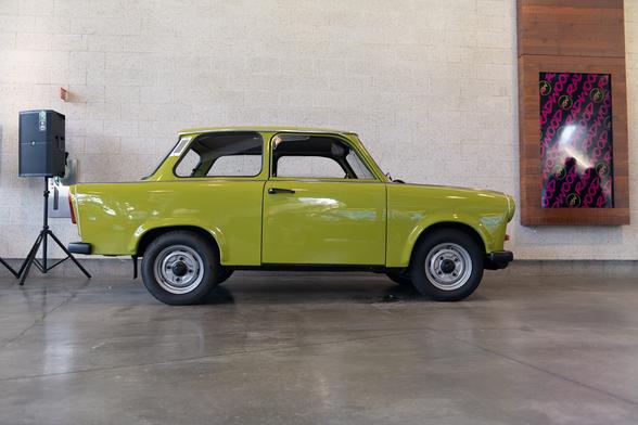 A chartreuse green compact, two-door sedan, parked indoors.