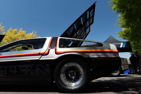 A silver coupe with bright orange tri-color stripes going down its body and up above the rear window. Its back-mounted engine cover is open.