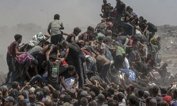 Un grupo de palestinos intentan conseguir sacos de harina de un camión de ayuda cerca de un punto de distribución de alimentos en Zikim, al norte de la Franja, este domingo. (MOHAMMED SABER / EFE)
