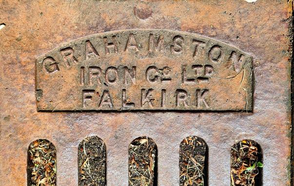 A cast iron drain cover with the words Grahamston Iron Co Ltd Falkirk on it.