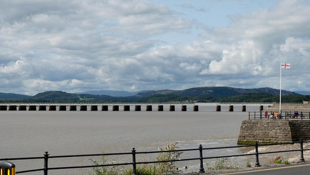 A view looking towards the fells of England's Lake District over the 475meter long railway viaduct at the village of Arnside in Cumbria (now Westmorland and Furness) on a breezy afternoon. July 2025. The viaduct spans the mouth of the River Kent as it enters the north side of Morecambe bay.
