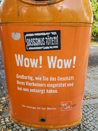 Noch ein orangener Mülleimer der Berliner Stadtreinigung, auf dem zu lesen ist: "Wow! Wow! Großartig, wie Sie das Geschäft Ihres Vierbeiners eingetütet und bei uns entsorgt haben."
(Auf einem weiteren Sticker ist zu lesen: "Rassismus tötet!")