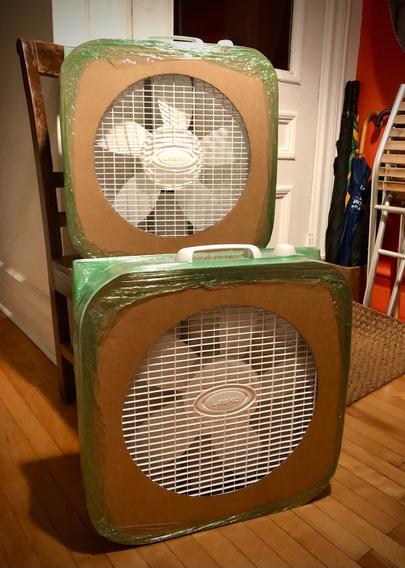 Deux purificateurs d'air bricolés maison. On voit les ventilateurs carrés recouvert d'un carton percé.