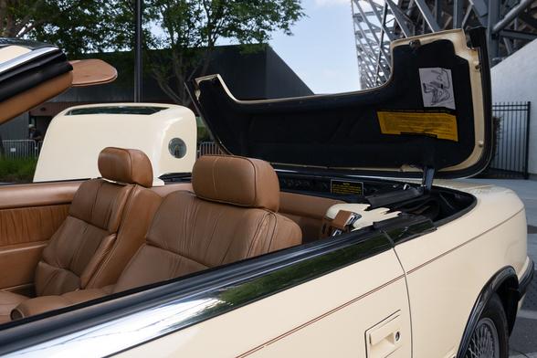 A look at the soft-top cover mechanism with the hardtop removed. The car has very plush, brown leather seats.