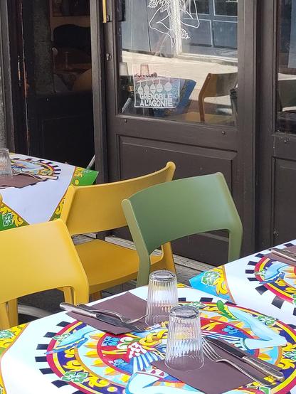 Une terrasse sur ce qui était un trottoir étroit et est maintenant partie d'une rue piétonne.
Dans la vitrine, l'affiche "Grenoble à l'agonie" dénonçant la piétonisation comme source de tous les maux du petit commerce.