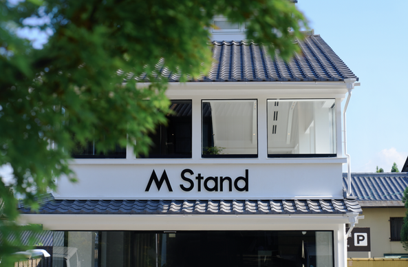 <p>スペシャルティコーヒーを提供する中国の新鋭カフェチェーン「M Stand（エムスタンド）」が7月26日、京都で初の海外直営店をオープンした。日本進出を皮切りに、アジアや世界市場へ広がっていく足がかりとする構えだ。</p>
<p>M Stand京都店は、歴史的な景観が色濃く残る南禅寺エリアに位置している。白と黒を基調としたスタイリッシュな店内は、京都の情緒とモダンな感性を融合させたデザインとなっている。2階には270度のパノラマウィンドウを設けており、四季折々の京都の風景を楽しめる仕様になっている。</p>
<p>海外1号店というのもあり、ローカライゼーションに特に力を入れている。京都産の抹茶や柚子、みかんを取り入れたオリジナルブレンドに加えて、スイカやキウイ、メロンを使ったオリジナルドリンクなどを開発した。ほかにも、地元企業の老舗和菓子店「金谷正廣」と共同開発した栗饅頭や、京都らしい「水占みくじ」も店舗の入り口に用意した。</p>
<p><img alt="" class="aligncenter size-full wp-image-357647" height="780" src="https://36krjp-1316517779.cos.ap-tokyo.myqcloud.com/uploads/2025/07/20250729225048screenshot757.png" width="1086" /></p>
<figure class="wp-caption aligncenter" id="attachment_357657" style="width: 2166px;"><img alt="" class="wp-image-357657 size-full" height="1404" src="https://36krjp-1316517779.cos.ap-tokyo.myqcloud.com/uploads/2025/07/20250729225820screenshot792.png" width="2166" /><figcaption class="wp-caption-text" id="caption-attachment-357657">白と黒を基調とした店内</figcaption></figure>
<p>さらに、トートバッグやマグカップ、パスポートケースといった限定デザインの雑貨も販売し、単なるカフェではなく、空間・商品・体験を通じて差別化を図る。</p>
<figure class="wp-caption aligncenter" id="attachment_357640" style="width: 1048px;"><img alt="" class="wp-image-357640 size-full" height="724" src="https://36krjp-1316517779.cos.ap-tokyo.myqcloud.com/uploads/2025/07/20250729224650screenshot981.png" width="1048" /><figcaption class="wp-caption-text" id="caption-attachment-357640">M Standが展開する周辺グッズ</figcaption></figure>
<p>M Standは2017年に上海で設立され、現在は中国39都市で560店舗以上に拡大している。店舗ごとに