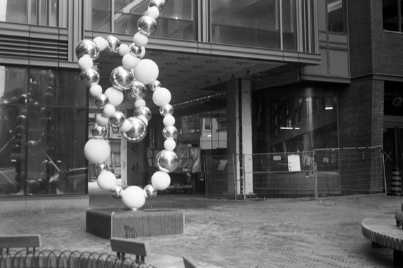 A large, whimsical sculpture like string loops of white and golden spheres stands in the courtyard of a condominium still under construction.