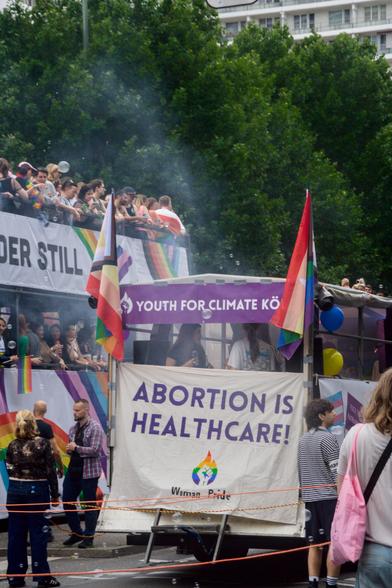 In front the truck of "Youth for Climate Köln" at CSD Berlin. They fixed a banner on it with "Abortion is Healthcare" and "Woman Pride" on it. There are also two progress-pride flags at the upper edges of the truck