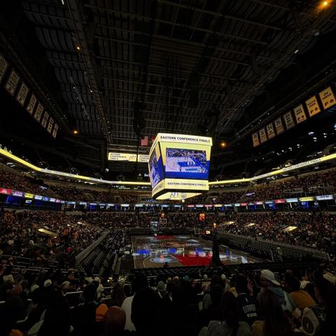 A photo from inside Gainbridge Fieldhouse for a packed virtual watch party of the Indiana Pacers. The game is projected on the Jumbotrons for attendees to watch.