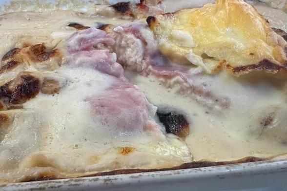 Escalope saboyano cortado, mostrando el pollo, jamón, la salsa de nata con champiñones y el queso tostado encima.