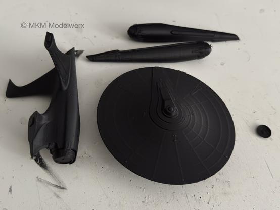 Black model parts on a white table.