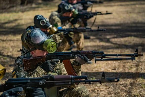[Illustrative photo] Civilian volunteers with chemical gas masks learn how to shoot with their rifles in a military training in the forests of Zaporizhzhia, Ukraine