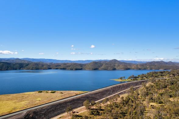 A drone shot, looking over the Wivenhoe damn wall and highway, towards Cormorant Bay on Lake Wivenhoe