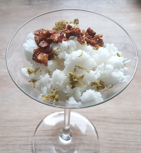 In einem Martiniglas die Schnee-artige Granita mit Limettenabrieb und Kokosknusperstückchen