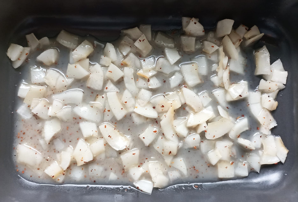 Die Kokos-Chips in einer Auflaufform mit der Flüssigkeit vor dem Backen