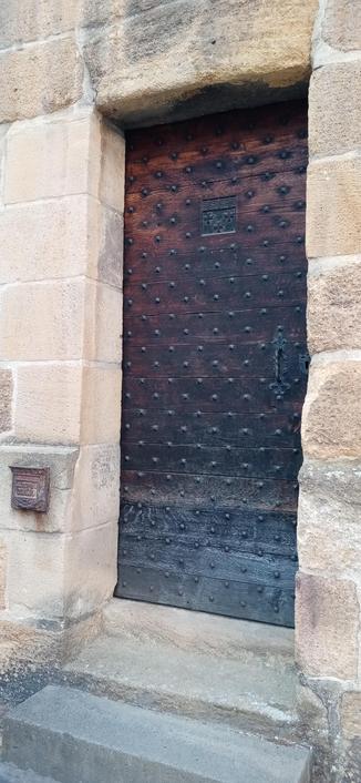 Quelques marches de pierre mènent à une vieille porte en bois, cloutée