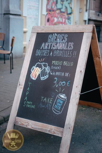 Chalkboard street sign, saying "BIERES ARTISANALES
BRASSÉES À BRUXELLES" and more