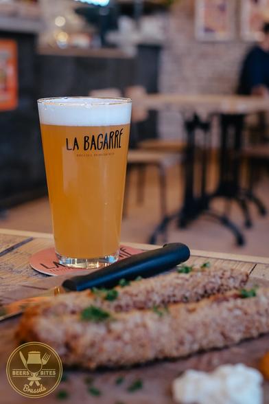 A glass of hazy beer, and in front of it, out of focus, two poulycrocs