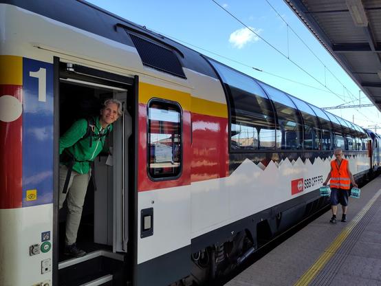 Woman standing on the balcony of a Swiss panorama train, looking outside while waiting for the train to leave.