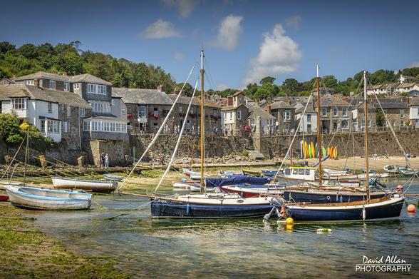 Boats in the scenic Cornish fishing harbour of Mousehole on a gorgeous summer's day.